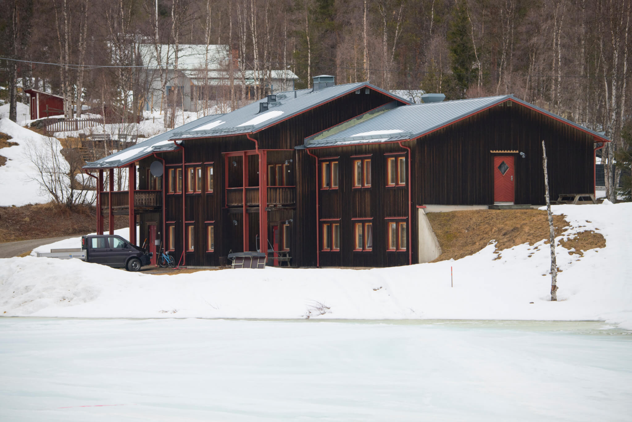 Vindelfjällens forskningsstation. Brunt hus med röda knutar i snö.