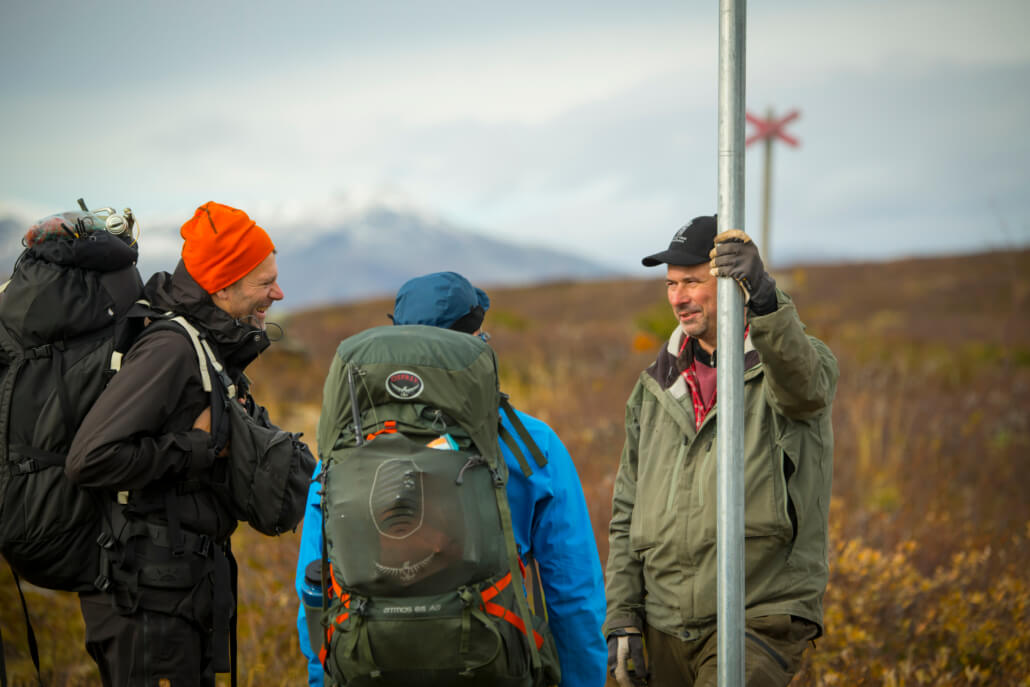 Två vandrare som står vid ett ledkryss och pratar med en naturbevakare. Naturbevakaren ler mot vandrarna.