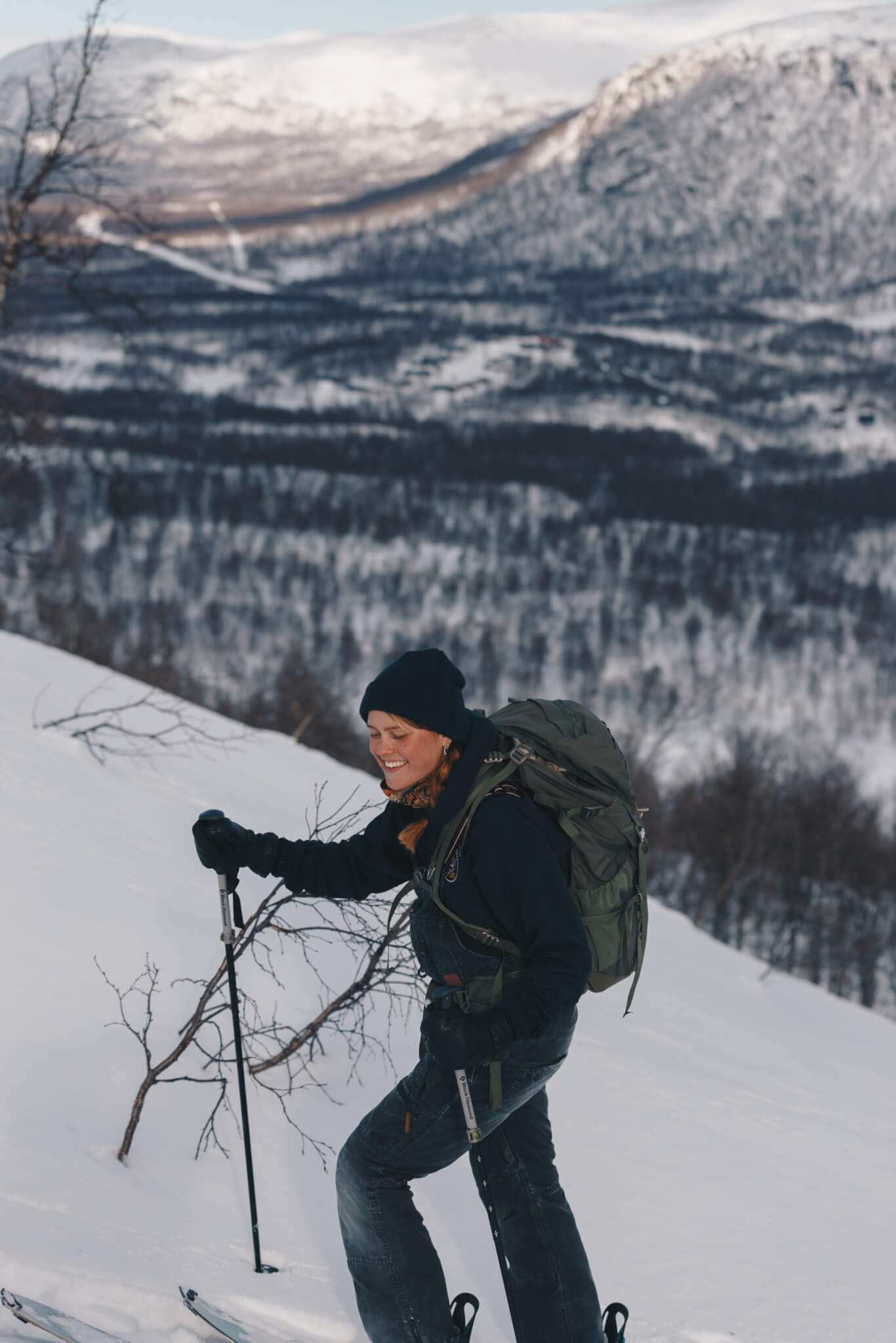 Kvinna går upp för fjäll på skidor.