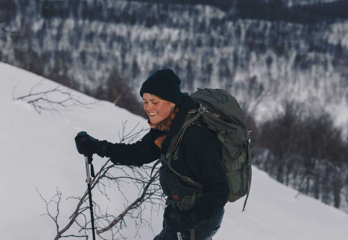 Kvinna går på skidor upp för bergsluttning.