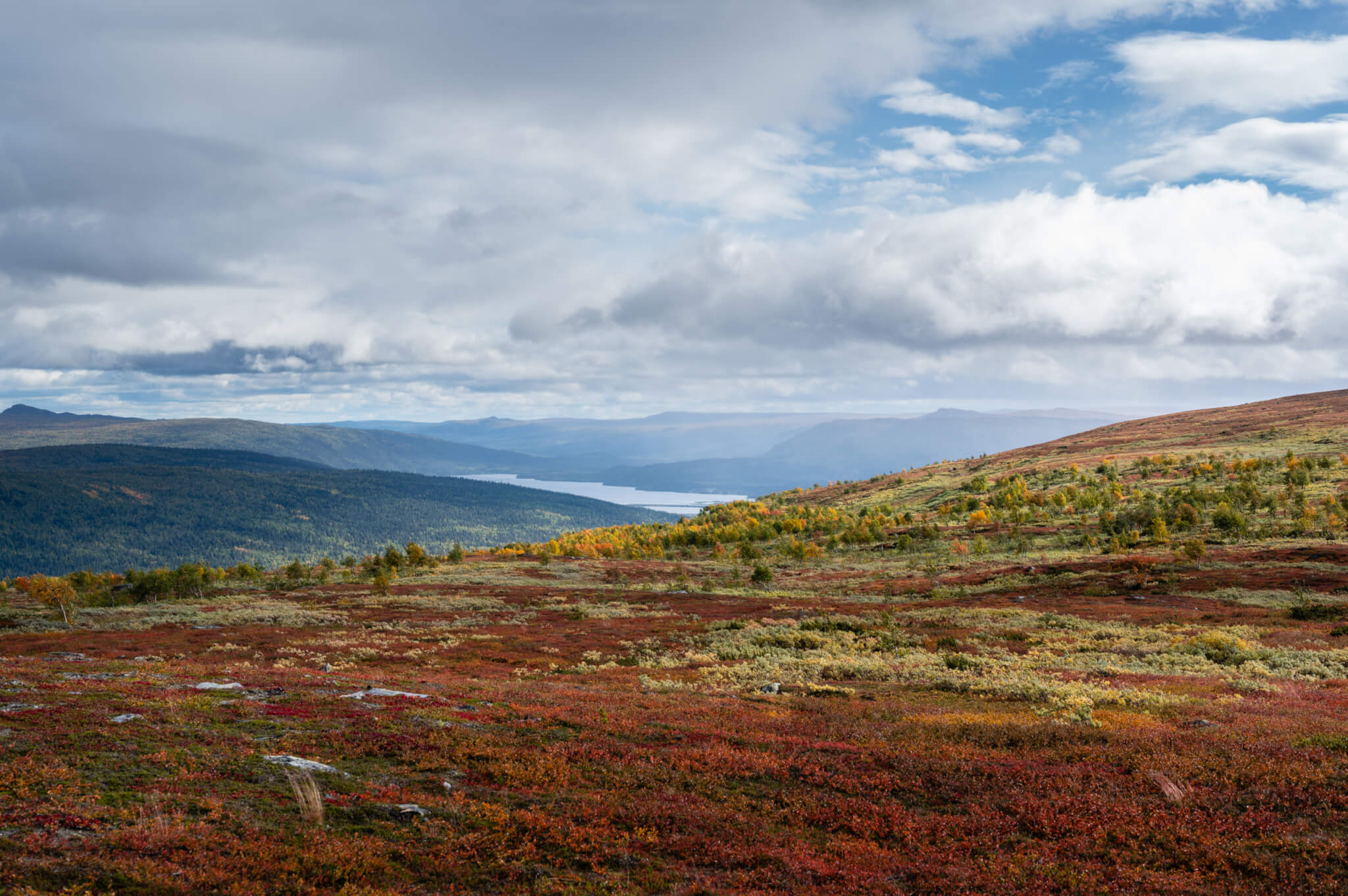 Utsikt mot en fjälldal med en sjö.