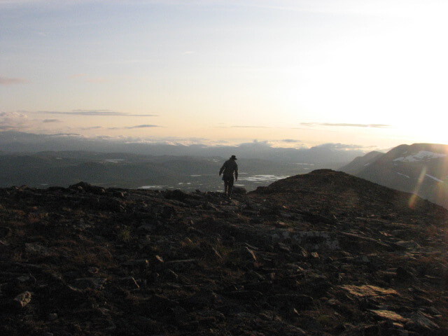 En person med hatt vandrar på en stenig fjällkam.